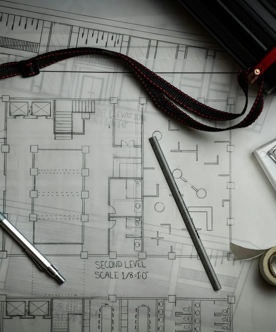 Grundriss mit Zeichenstiften, Lineal und Planrolle auf einem Arbeitstisch